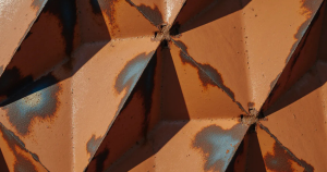 Featured image for "This Was Never About the Costume": Rusted pentagonal facets with rot spreading beneath a polished surface